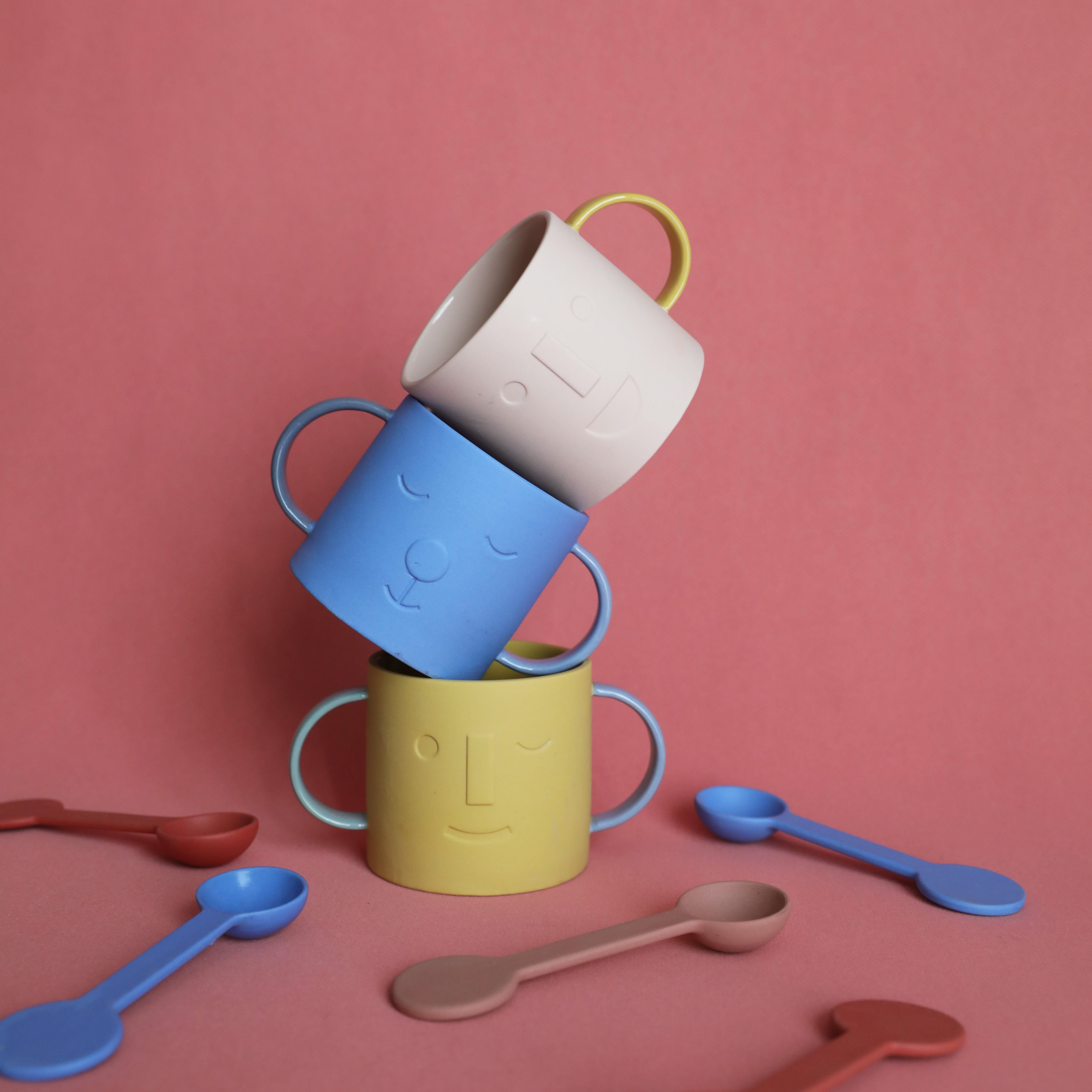 Matte clay ceramic mug with a subtle embossed face and contrast-color double handles