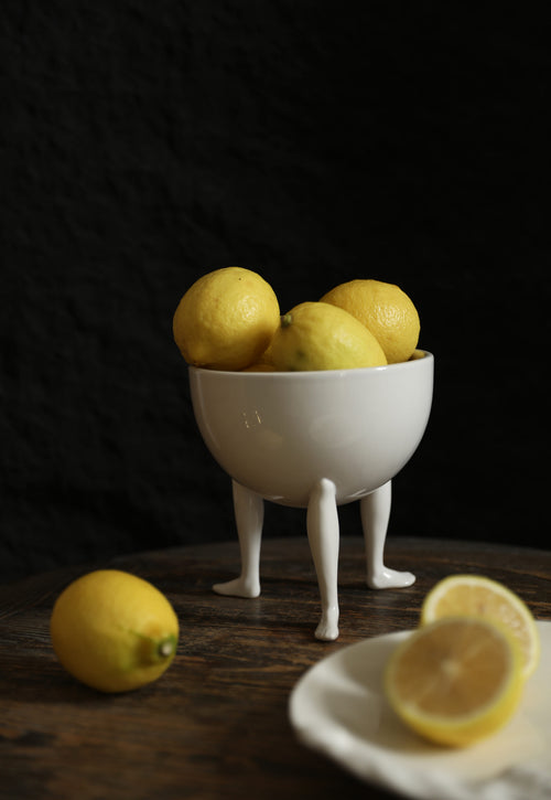 Sculptural white ceramic fruit bowl standing on three delicate legs
