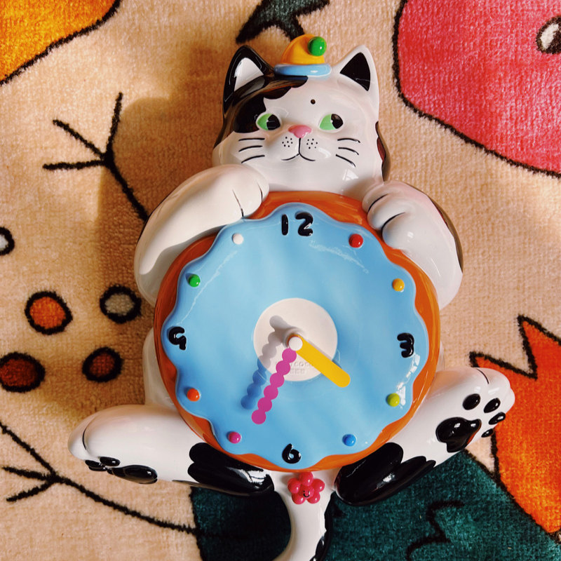 Hand-painted cat wall clock cradling a frosted donut timepiece