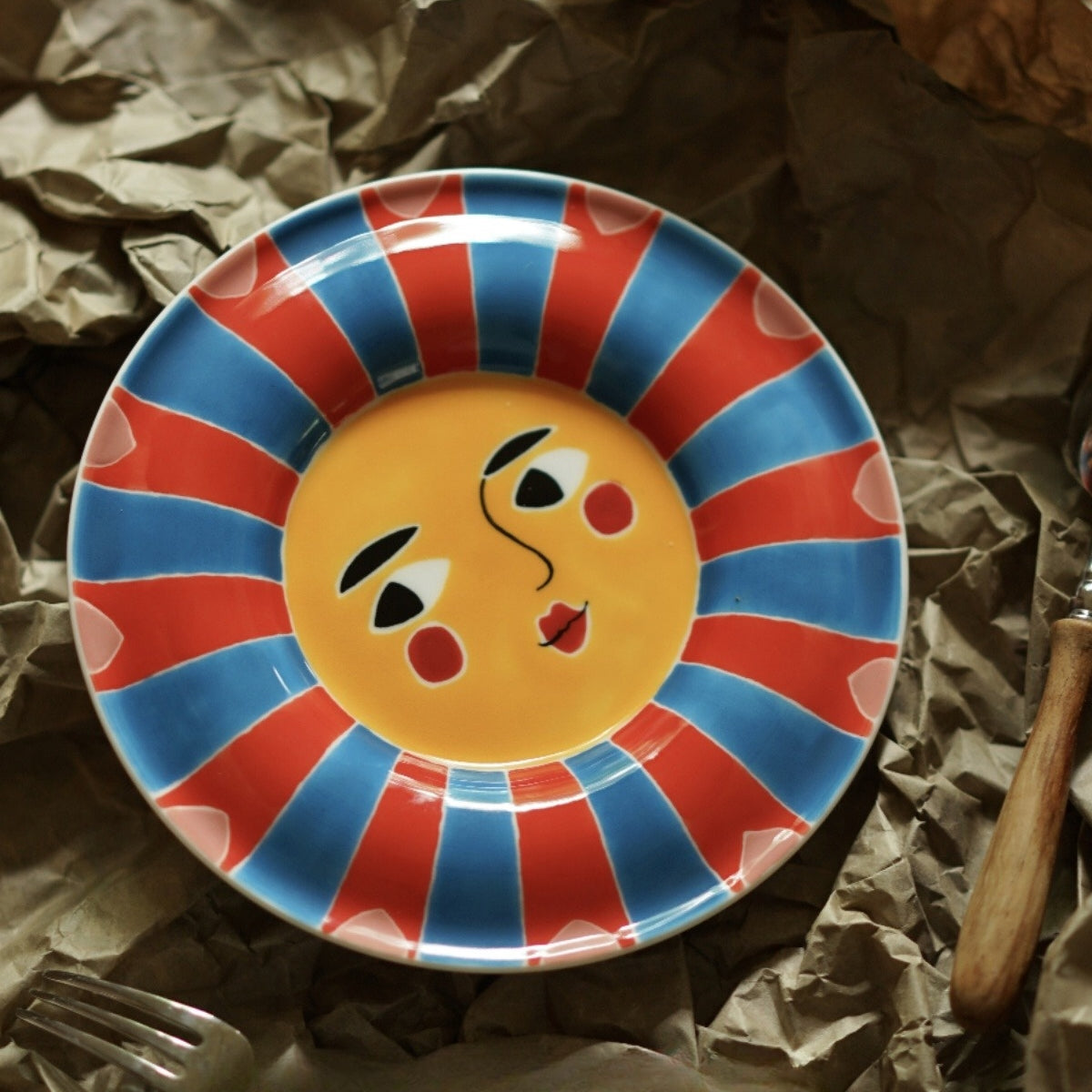 Ceramic plate with a vibrant sunburst pattern and a cheerful face