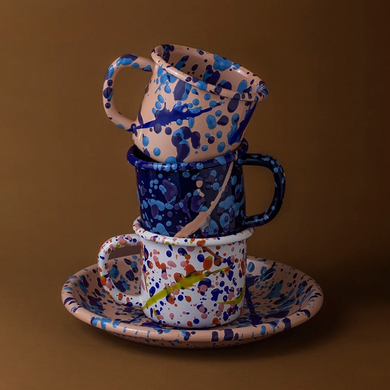 Paint-splattered enamel mug that throws confetti every time you pick it up